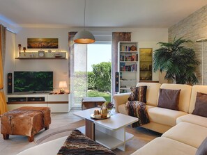 A modern living room with a flat-screen TV, a bookshelf, a sofa, and a coffee table. - Villa in Novigrad With Pool Near Beach (Novigrad)