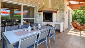 An outdoor dining area with a stone wall, a brick fireplace, and a wooden ceiling. - Villa in Novigrad With Pool Near Beach (Novigrad)