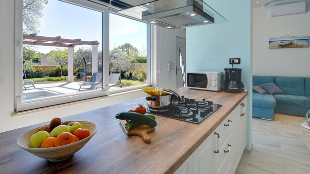 Una cocina moderna con un amplio ventanal, una encimera de madera y una estufa integrada.