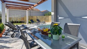 Un patio al aire libre con una mesa de vidrio, sillas y un centro de mesa con girasoles.