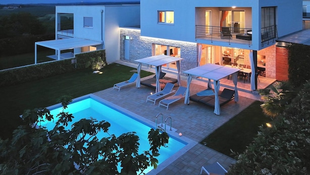 Ein modernes, zweistöckiges Haus mit Swimmingpool, Außenbereich und einer Fassade aus Stein.
