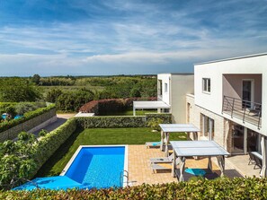 Eine moderne Villa mit Swimmingpool, Sitzgelegenheiten im Freien und Blick auf die Landschaft.