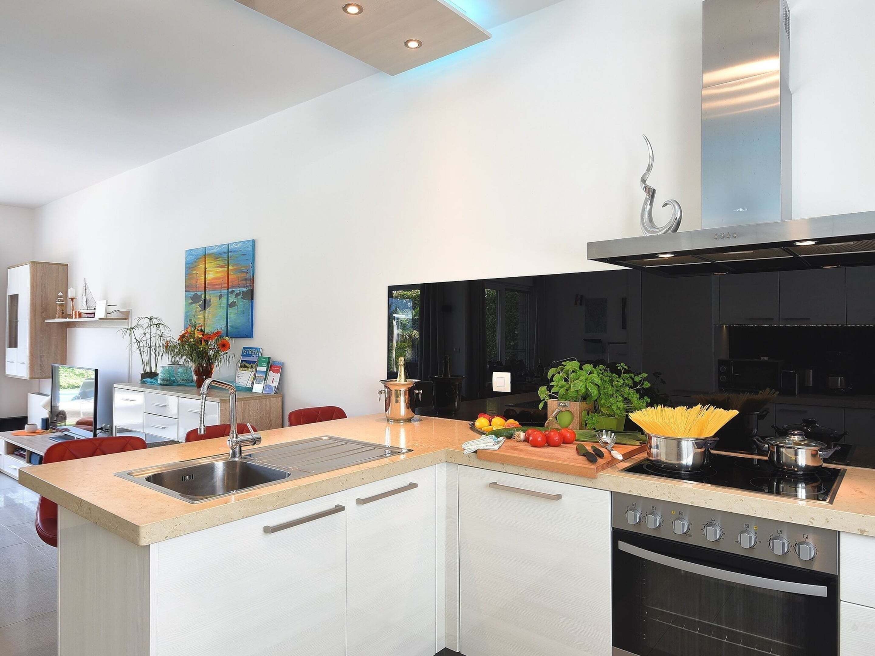 A modern kitchen with a central island, stainless steel appliances, and a view of the outdoors.