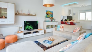 Ein modernes Wohnzimmer mit Fernseher, Sofa, Couchtisch und Dekorationselementen.
