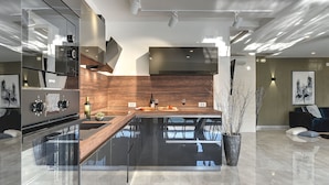 A modern kitchen with a central island, stainless steel appliances, and a wooden backsplash. - Holiday Home in Rovinj With Pool and Sauna (Rovinj)