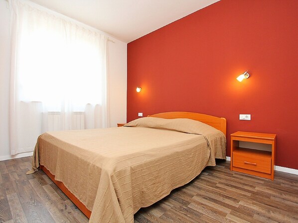 Une chambre à coucher avec un lit, une table de chevet en bois et deux lampes fixées au mur.