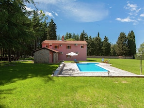 A pink house with a swimming pool, surrounded by a grassy lawn and trees. - Rural Villa With Swimming Pool (Vrsar)