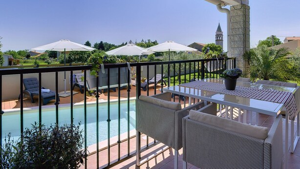 Un balcon avec une piscine, du mobilier d’extérieur et des parasols.