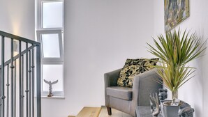 Un salon avec un canapé gris, une table basse et un escalier doté d’une rampe en métal.