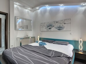 Une chambre à coucher moderne avec un lit, une commode, un miroir et des œuvres d’art murales.