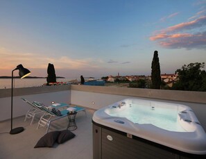 Una terrazza sul tetto con idromassaggio, poltrone relax e una lampada.