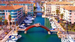 Un puerto deportivo con barcos amarrados, un puente peatonal y edificios con balcones.