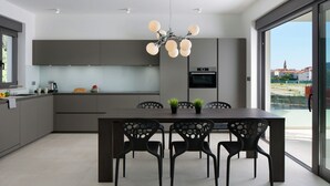 Una cocina moderna con una isla central, un comedor con cuatro sillas y un amplio ventanal con vistas al exterior.