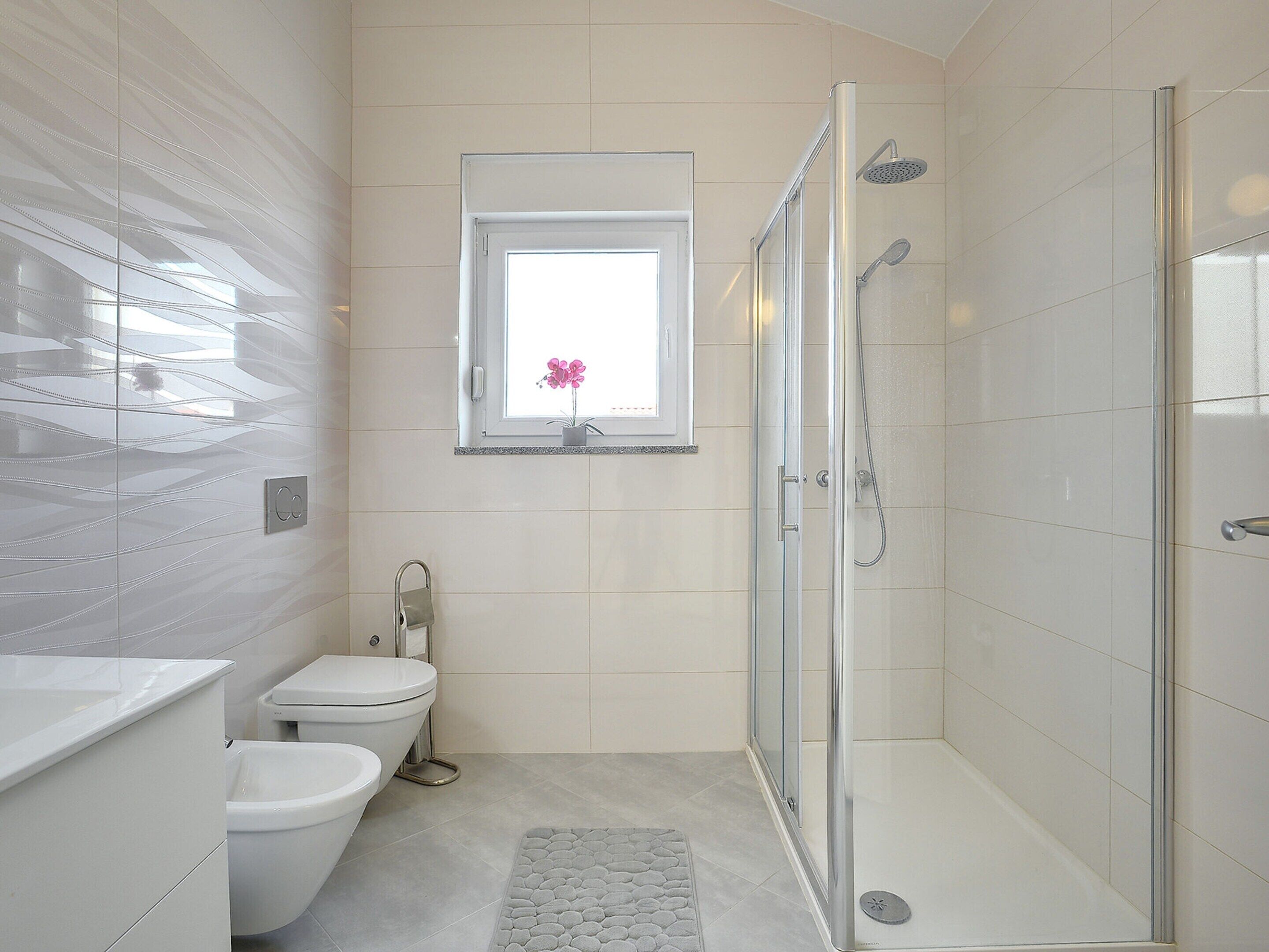 A modern bathroom with a glass shower enclosure, a toilet, and a vanity with a mirror.