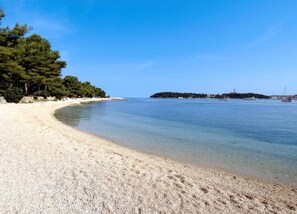 A beach with clear water, a sandy shore, and a small island in the distance. - Villa in Rovinj With Pool and Sauna (Rovinj)