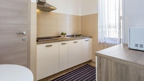 A modern kitchen with a built-in stove, a sink, and a window with sheer curtains. - Apartment in Pula Near the Sea and Town Center (Pula)