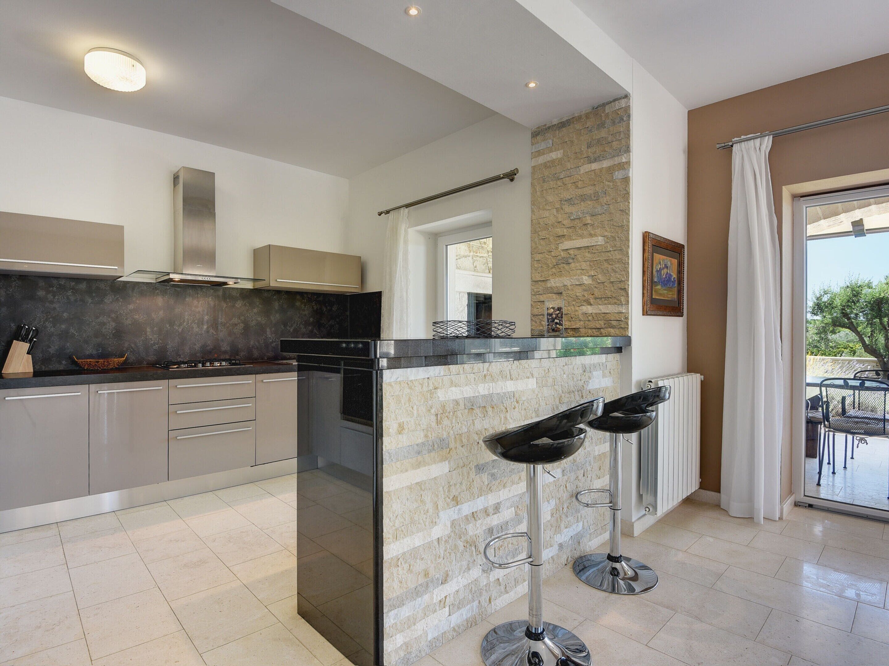 Una cocina moderna con una isla central, electrodomésticos de acero inoxidable y una pared de acento de piedra.