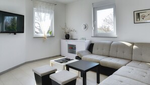 A modern living room with a sofa, two ottomans, a coffee table, and a TV mounted on the wall. - Holiday Home Vodnjan Near Beach (Svetvincenat)