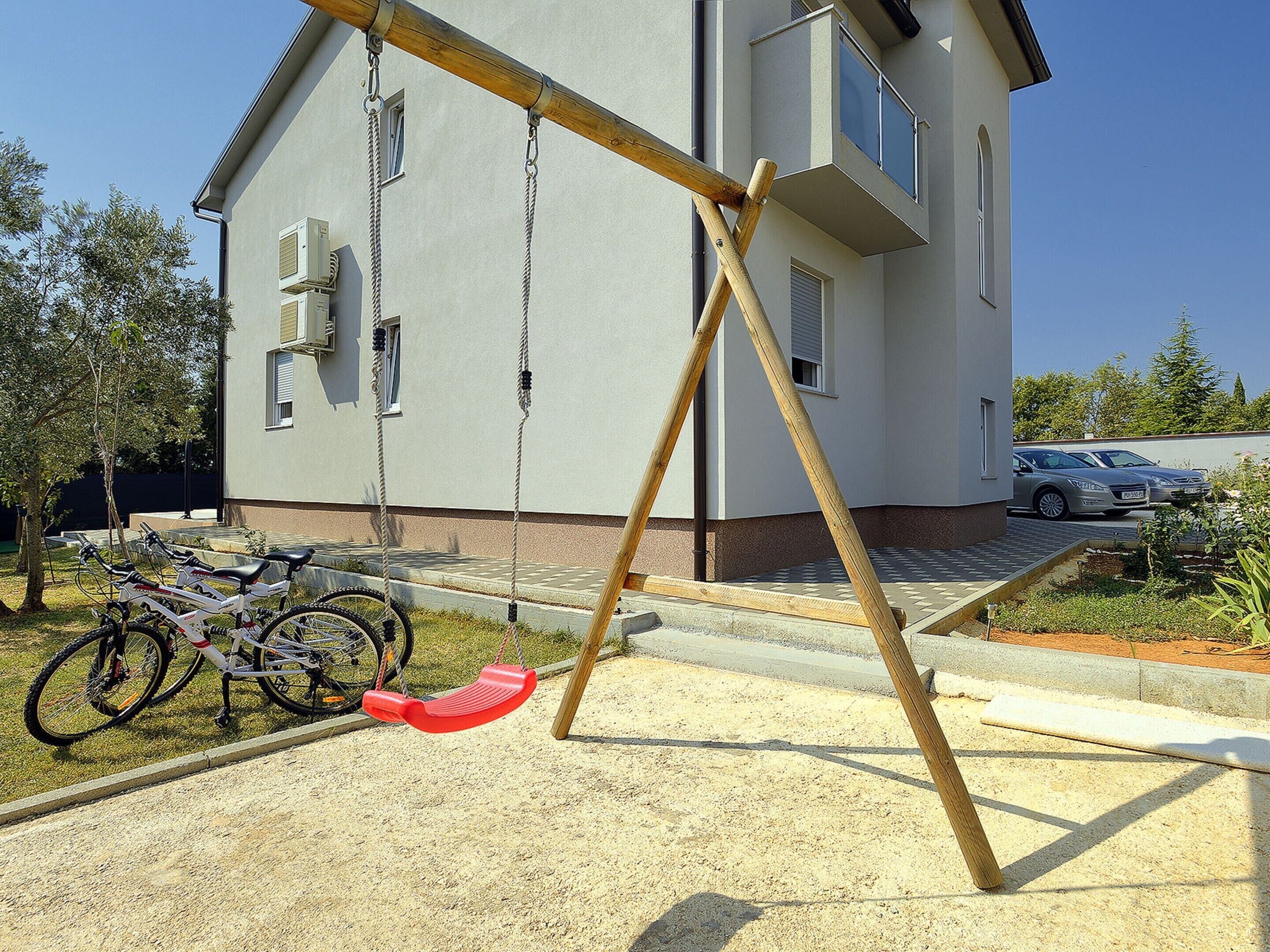 Un quartier résidentiel avec une balançoire, des vélos et une voiture garée.