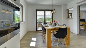 Une cuisine moderne dotée d’un four encastré et d’un coin repas avec une table et des chaises en bois.