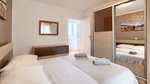 A modern hotel room with a large bed, a bedside table, a mirror, and a wardrobe with a cityscape mirror. - Holiday Home in Rovinjsko With Pool (Rovinj)