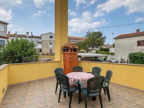 A balcony with a table and chairs, a brick chimney, and a view of neighboring houses. - Holiday Home in Rovinjsko With Pool (Rovinj)