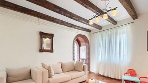 A living room with a beige sofa, a wooden coffee table, and a red chair. - Holiday Home in Rovinjsko With Pool (Rovinj)