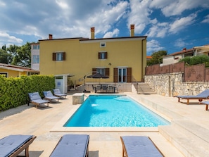A two-story building with a swimming pool, outdoor seating, and a stone wall. - Holiday Home in Rovinjsko With Pool (Rovinj)