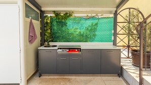 A compact outdoor kitchen with a built-in sink, a gas stove, and a countertop. - Holiday Home in Rovinjsko With Pool (Rovinj)