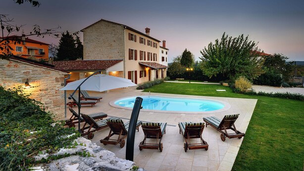 Une piscine avec des chaises longues et un mur en pierre.