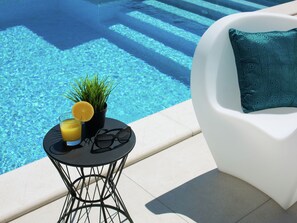A poolside setting with a small table holding a drink, sunglasses, and a plant. - Apartment in Fazana Near Beach and Pool (Fazana)