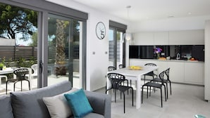 A modern kitchen with a dining area, a sofa with cushions, and a large window. - Apartment in Faana With Sea Beach (Fazana)