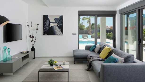 A modern living room with a grey sofa, a coffee table, and a TV on the wall. - Apartment in Faana With Sea Beach (Fazana)