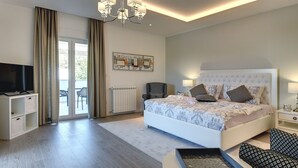 Een moderne slaapkamer met een groot bed, een televisie, een stoel en uitzicht op de omgeving.