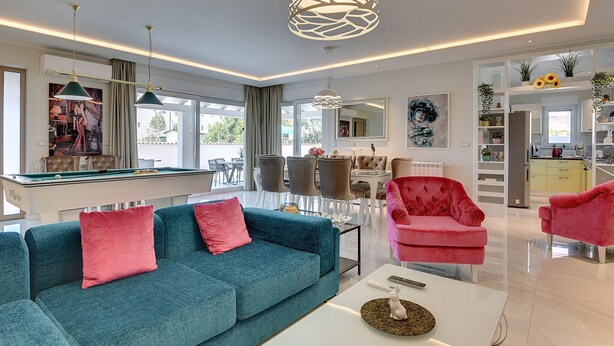 Een moderne woonkamer met een pooltafel, een bank en een eethoek.