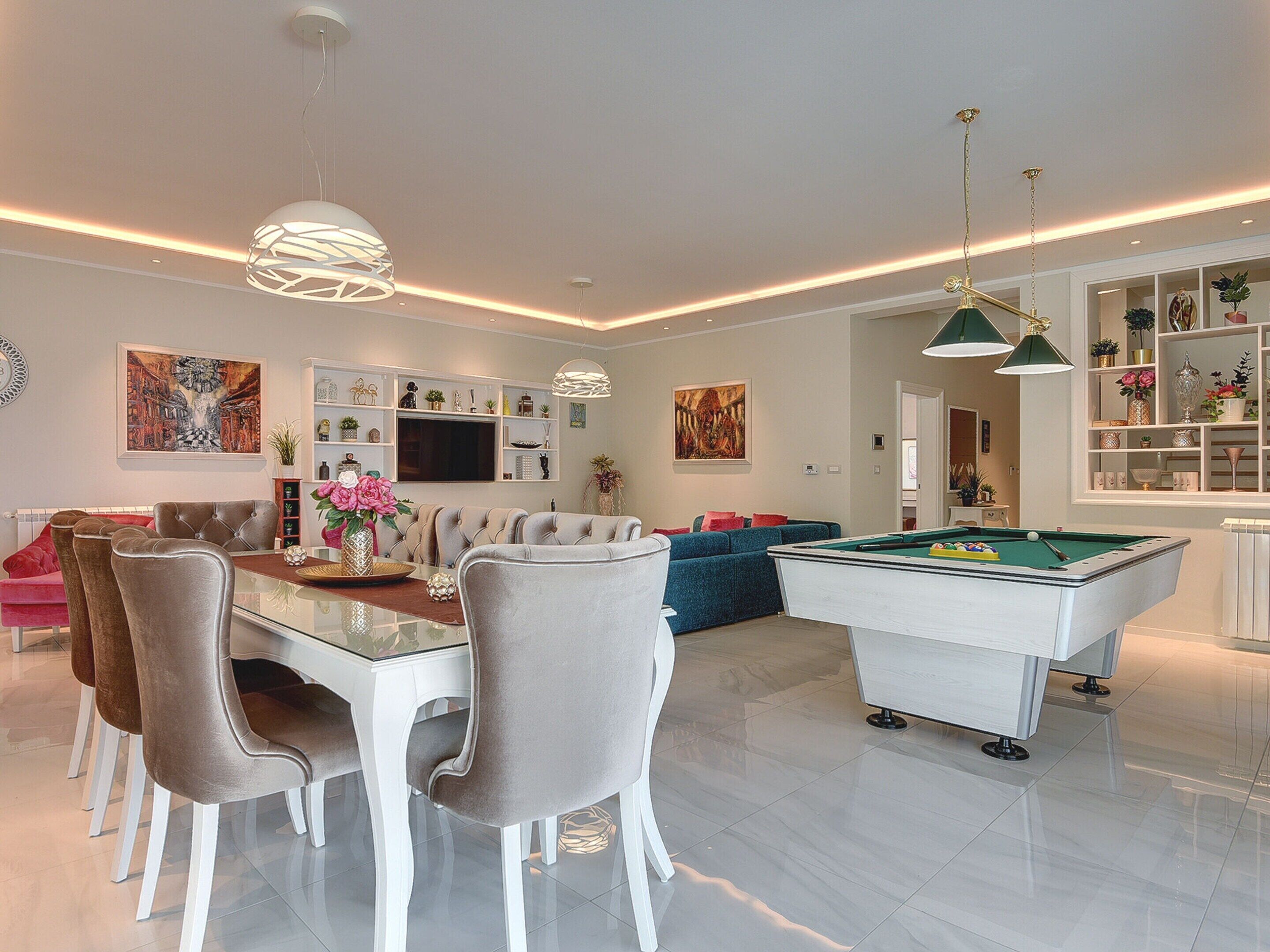 A modern living room with a pool table, comfortable seating, and a dining area.