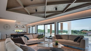 A spacious living area with two sofas, a coffee table, and a dining table. There is a large window providing a view of the outdoors. - Villa in Vodnjan With Garden (Vodnjan)