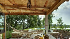 Une table en bois sur laquelle se trouvent un plateau de pommes, une bouteille et un bocal de noix.
