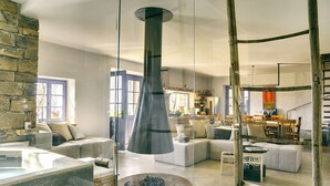 Un salon moderne avec un mur en pierre, une grande fenêtre et un coin repas doté de meubles en bois.