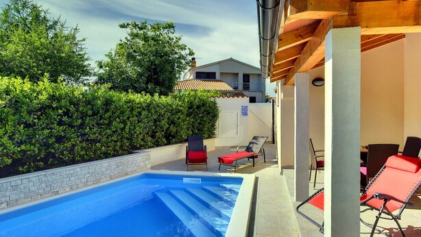 A swimming pool with lounge chairs and a covered patio area. - Detached Modern Villa With Pool and Fenced Yard Near the Sea (Liznjan)