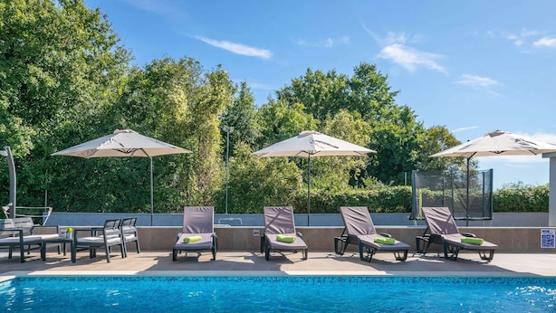 A swimming pool with lounge chairs and umbrellas, surrounded by trees. - Detached Holiday Home With Swimming Pool, Near the Beach (Marcana)