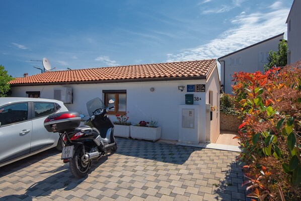 A residential building with a tiled roof, a parked car, and a motorcycle. - Holiday Home in Medulin Near Beach (Medulin)