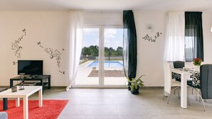 A modern living room with a TV, a dining table, and a red rug. - Detached Villa With Pool and Large Garden in Quiet Area Near the Sea (Barban)