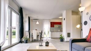 A modern living room with a sofa, a coffee table, and a dining area with chairs and a table. There is a kitchen with red cabinets and a dining area with a table and chairs. - Detached Villa With Pool and Large Garden in Quiet Area Near the Sea (Barban)