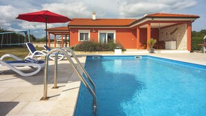 A swimming pool with a metal ladder, lounge chairs, and a red umbrella. - Detached Villa With Pool and Large Garden in Quiet Area Near the Sea (Barban)