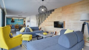 A modern living room with a sofa, yellow armchair, and a dining area with a kitchen in the background. - Villa in Liznjan With Pool Near the Beach (Liznjan)