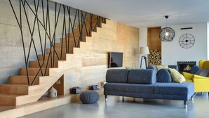 A modern living room with a wooden staircase, a sofa set, and a fireplace. - Villa in Liznjan With Pool Near the Beach (Liznjan)