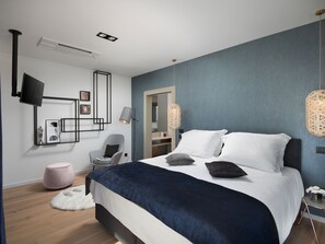 A modern bedroom with a large bed, a flat-screen TV, a chair, and a small table with a vase of flowers. - Villa in Pula With Pool Near Roman Ruins (Medulin)