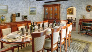 A dining room with a stone wall, wooden furniture, and a chandelier. - Holiday Home in Rojnici With Private Pool (Barban)