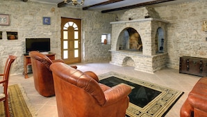 A stone-walled living room with leather sofas, a fireplace, and a chandelier. - Holiday Home in Rojnici With Private Pool (Barban)